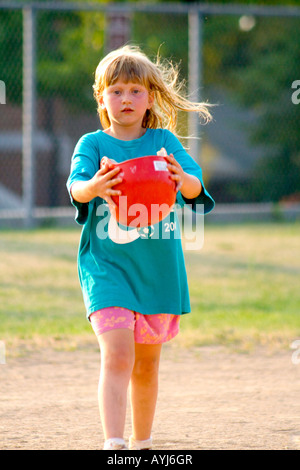 Girl age 7 walking on baseball field with helmet. Groveland School Field St Paul Minnesota USA Stock Photo