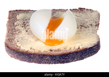 A shelled runny boiled egg on buttered wholemeal bread Stock Photo