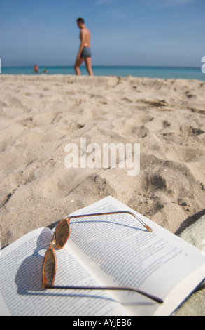 Open book and sunglasses on beach towel Stock Photo - Alamy