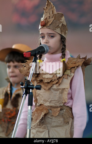 Young Girl Speaking on a Microphone During a Performance by School Children Stock Photo