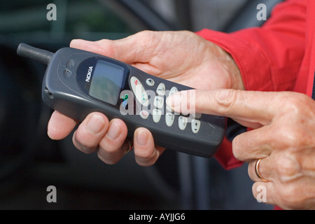 Close up of womans finger dialing on old Nokia mobile phone UK Stock Photo