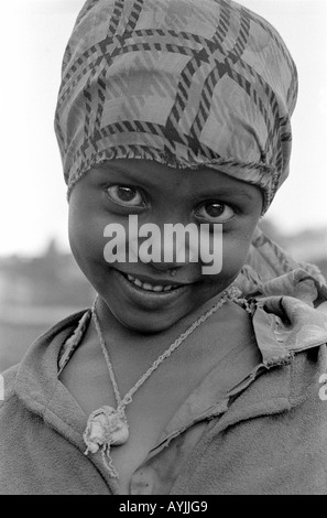 B/W portrait of a beautiful, shy and smiling Ethiopian Muslim girl with headscarf and wearing an amulet. Harar, Eastern Ethiopia, Africa Stock Photo
