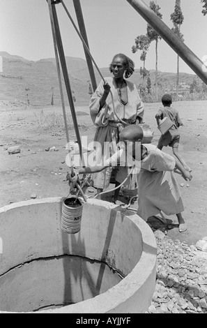 B/W of a Tigrayan woman and children lifting clean drinking water from a new, hand-dug well. Tigray, Ethiopia Stock Photo