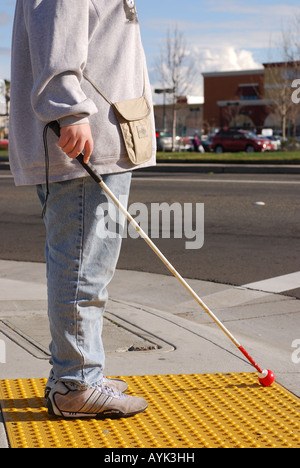 Blind woman standing on a crosswalk platform waiting to cross the street Stock Photo