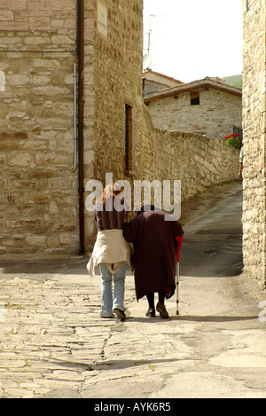 Young woman helps and old woman Gubbio Italy Vertical upright portrait Stock Photo