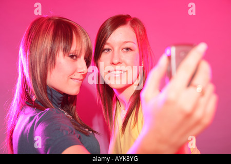 two 17 year old teenage girls taking a picture of themselves with a mobile phone. Stock Photo