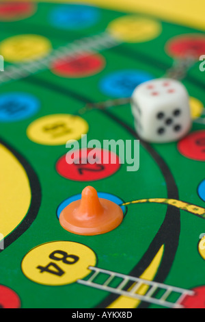 dice and piece on snakes and ladders board game Stock Photo