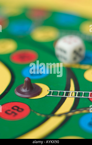 dice and piece on snakes and ladders board game Stock Photo