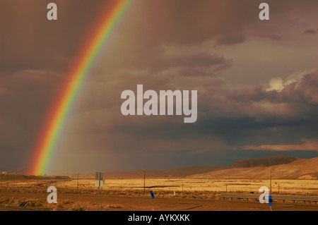 Rainbow emerging from the town of Elko Nevada in a rain storm over farmland and desert Stock Photo