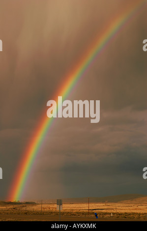 Rainbow emerging from the town of Elko Nevada in a rain storm over farmland and desert Stock Photo