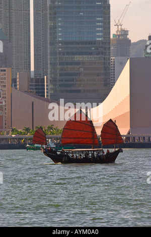 A junk sailing in Victoria Harbor with Cultural Center building in the background Hong Kong China Stock Photo