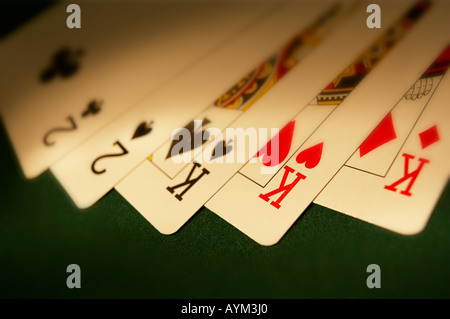 HAND OF PLAYING CARDS SHOWING FULL HOUSE ON GREEN CLOTH GAMING TABLE Stock Photo