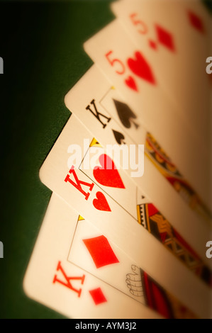 HAND OF PLAYING CARDS SHOWING FULL HOUSE ON GREEN CLOTH GAMING TABLE Stock Photo