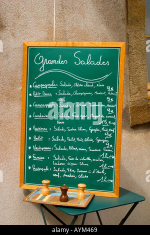 A menu stands on a table displaying a selection of salads outside a restaurant in Burgundy, France Stock Photo