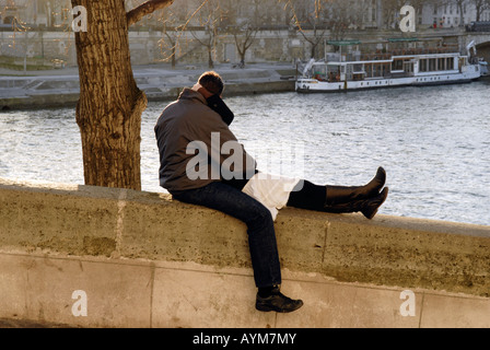 Lovers kissing along the Seine River in Paris with a barge in the background Stock Photo