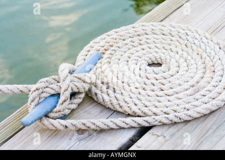 Coiled mooring line tied around cleat on a wooden dock Stock Photo