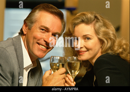 Happy middle aged couple toasting with wine glasses in restaurant Stock Photo