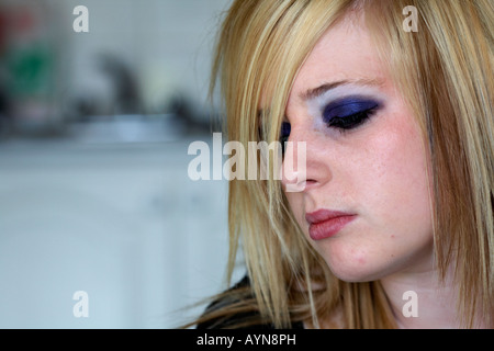 close up of face of teenage blonde haired woman sitting crying in her kitchen bedsit Stock Photo