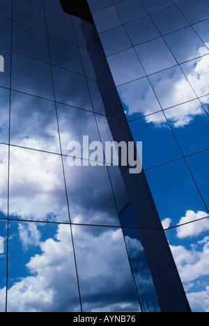 Contemporary glass and steel office tower reflecting clouds and blue sky Stock Photo