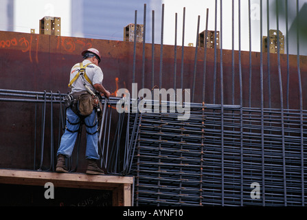 Steel worker wearing hardhat and safety harnesses working with rebar on an office tower construction site Stock Photo