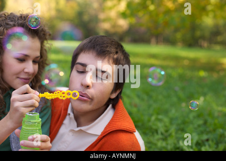 Teenage boy and girl making soap bubbles, close-up, selective focus Stock Photo
