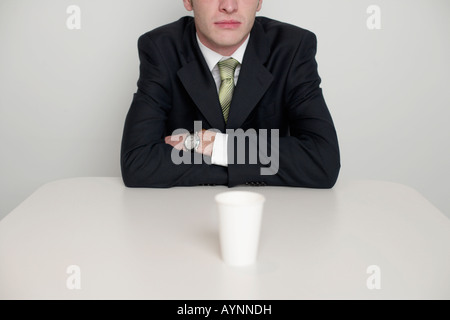 Businessman at desktop, a cup standing in front Stock Photo