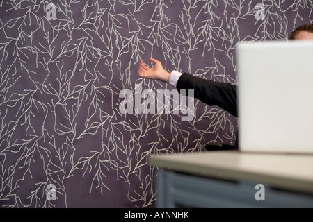 Businessman sitting in front of his laptop, stretching his arms Stock Photo