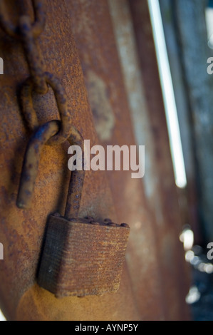 An open, rusty padlock against rusted corrugated iron Stock Photo