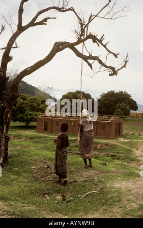 Old woman and young girl gathering firewood - village of Chembe, Cape Maclear, Lake Malawi, Malawi Stock Photo