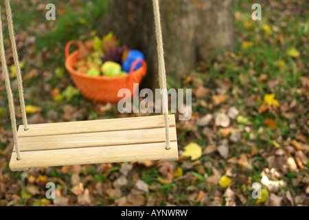 Picnic basket behind a wooden swing in front of a deciduous tree, close-up, selective focus Stock Photo