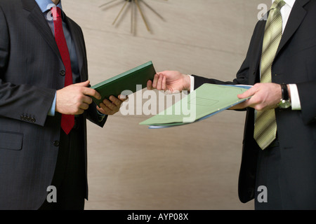 Two businessman standing in an office, handing over documents Stock Photo
