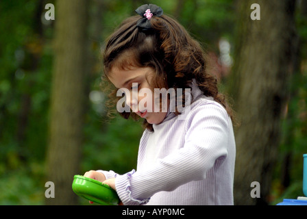 Three year old girl soft outdoor setting cooking with a toy kitchen set Stock Photo