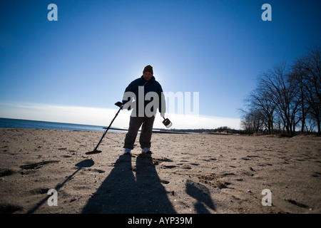 Man using a metal detector on a Beach in West Haven Connecticut USA Stock Photo