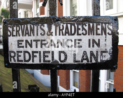 LONDON, UK. An old sign for servants and tradesmen on the railings outside flats in the Royal Borough of Kensington and Chelsea. Stock Photo