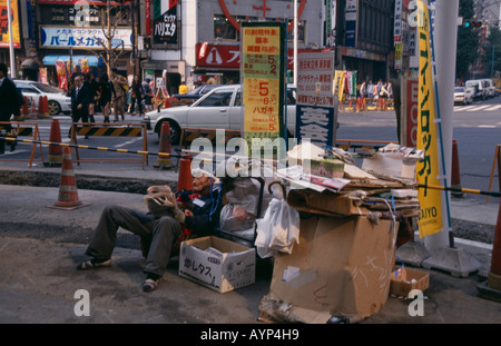 JAPAN Honshu Tokyo Homeless man living on the street with his cardboard home at a busy road junction. Stock Photo