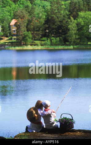 Boy and girl cuddling on lakeside fishing picnic in Sweden Stock Photo