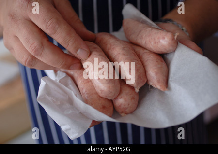 A butcher holding sausages and placing them in a bio bag in Modbury, South Devon, UK. Stock Photo