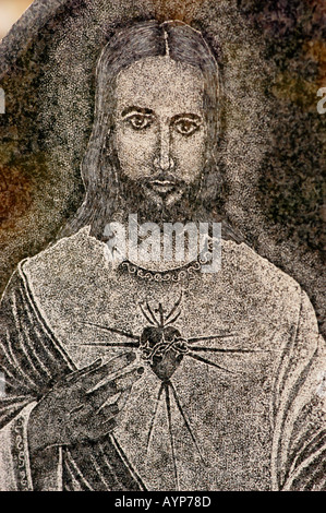 Jesus Christ stone bass relief with his hand pointing to his heart with rays Stock Photo