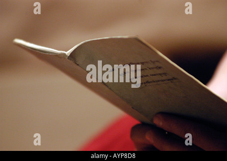 Close-up of hands holding an open book with text, reading in soft light against a blurred background. Stock Photo
