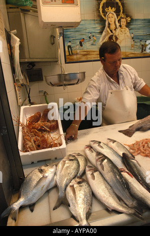 A fishmonger works at the central market in Malaga Andalusia Spain, surrounded by fresh fish and seafood displays in the traditional market interior. Stock Photo