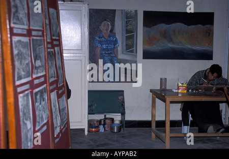 An artist working in a studio surrounded by paintings and sketches in Dharamsala, Himachal Pradesh, India. Stock Photo