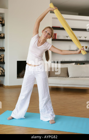 A blonde woman holds a towel as she stretches herself while exercising ...