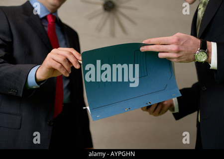 Two businessman standing in an office, handing over documents Stock Photo