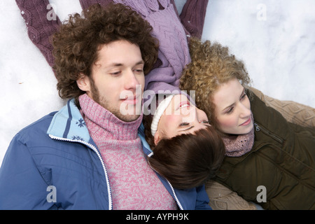 Three young people lying next to each other in the snow Stock Photo