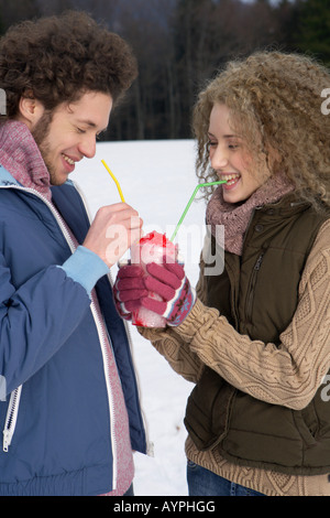 Young man and woman drinking crushed ice of the same beaker, close-up Stock Photo