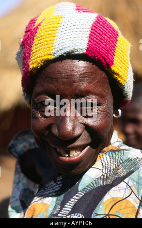 Colourful portrait of an elderly, laughing African woman wearing a striped wooly hat looking to camera. Zaka, Zimbabwe Stock Photo