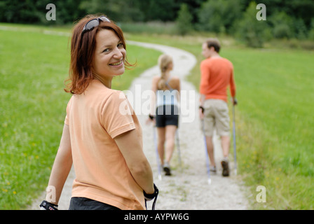 Young woman Nordic walking (ski walking) behind a couple Stock Photo