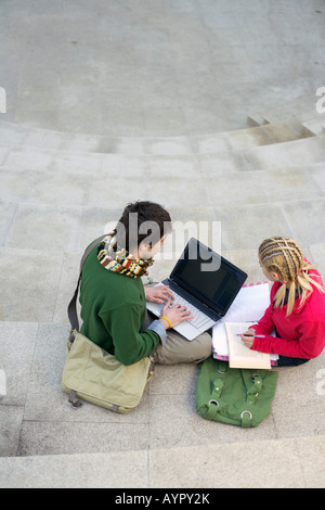 Young couple using a laptop on a staircase Stock Photo