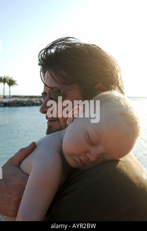 Netherlands Antilles Curacao a baby boy sleeping in the arms of his father Stock Photo