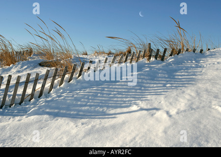 Snow fence on a sand dune nearly covered with snow in winter Stock Photo